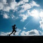 Silhouette of a person running up stairs with a bright blue sky and clouds in São Paulo, Brazil.